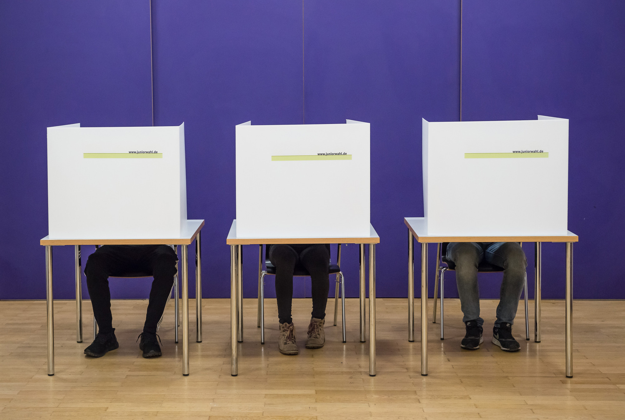 Bild von drei Wahlkabinen der Juniorwahl mit Schülern in den Wahlkabinen